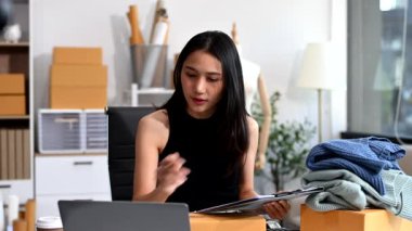  Moda tasarımcısının masasında dizüstü bilgisayar kullanan Asyalı genç bir kadın. 