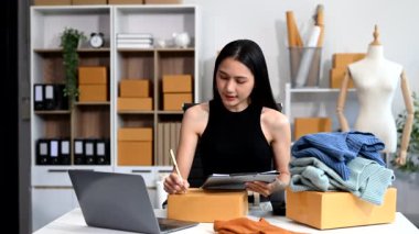  Moda tasarımcısının masasında dizüstü bilgisayar kullanan Asyalı genç bir kadın. 