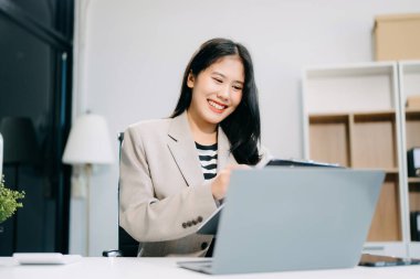 Ofisteki masada çalışan iş kadını dizüstü bilgisayar kullanıyor ve panoya yazı yazıyor. 