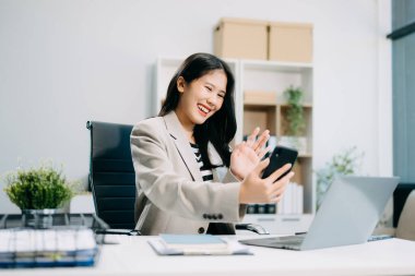 Ofisteki masada çalışan iş kadını dizüstü bilgisayar ve akıllı telefon kullanıyor. 