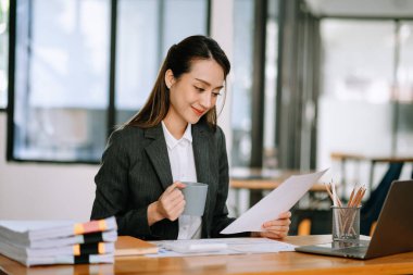 Modern ofisteki belge ve dizüstü bilgisayarlarda finansmanı analiz eden başarılı Asyalı iş kadını 
