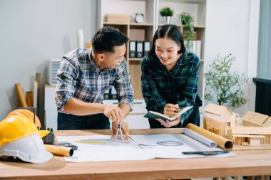 Asyalı mühendisler miğferler, planlar, ofis modelleri ile birlikte mimari projeler üzerinde tartışıyor ve birlikte çalışıyorlar. Modern ofiste Asya endüstrisi profesyonel takımı.