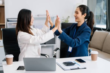 Ofiste çalışan iki Asyalı iş kadını beşlik çakıyor.  