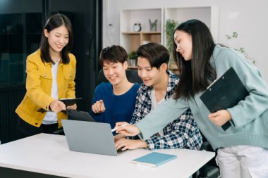  Genç işletme yaratıcı ekibi ofiste otururken ve dizüstü bilgisayar ve dijital tablet kullanarak beyin fırtınası yapıyor, plan yapıyor ve tartışıyorlar. 