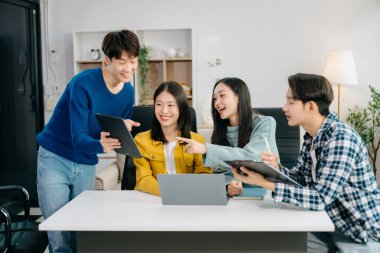  Genç işletme yaratıcı ekibi ofiste otururken ve dizüstü bilgisayar ve dijital tablet kullanarak beyin fırtınası yapıyor, plan yapıyor ve tartışıyorlar. 