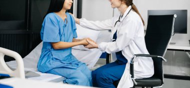 Kadın doktor kadının eline dokunuyor, hastanede ya da klinikte bakım konsepti uyguluyor. 