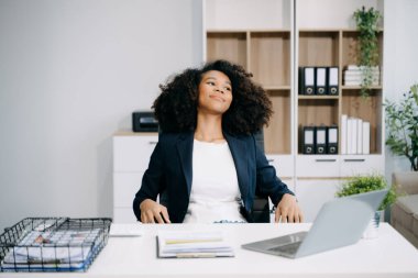 Ofis masasında dizüstü bilgisayarla uzun bir gün geçirdikten sonra boynu ağrıyan genç bir iş kadını. 