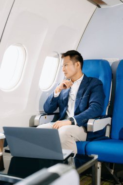 Genç Asyalı yönetici birinci sınıfta dizüstü bilgisayar ve kahvede başarılı.. 