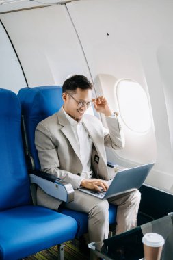 Genç Asyalı yönetici birinci sınıfta dizüstü bilgisayar ve kahvede başarılı.. 