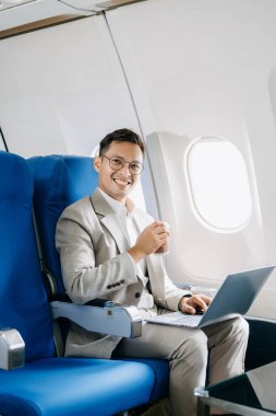 Genç Asyalı yönetici birinci sınıfta dizüstü bilgisayar ve kahvede başarılı.. 
