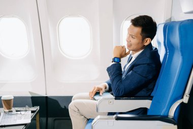 Genç Asyalı yönetici dizüstü bilgisayar, akıllı telefon ve kahveyle birinci sınıfta başarılı oldu. 