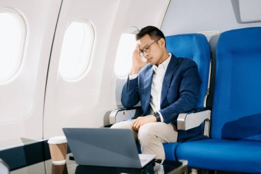 Genç Asyalı yönetici birinci sınıfta dizüstü bilgisayar ve kahvede başarılı.. 