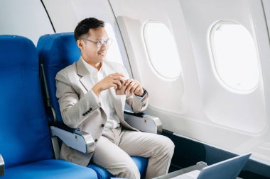 Genç Asyalı yönetici birinci sınıfta dizüstü bilgisayar ve kahvede başarılı.. 