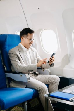 Genç Asyalı yönetici dizüstü bilgisayar, akıllı telefon ve not defteriyle birinci sınıfta başarılı oldu