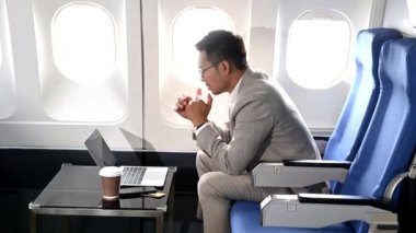 Genç Asyalı yönetici birinci sınıfta dizüstü bilgisayar ve kahvede başarılı.. 