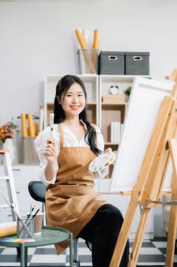 Sanat atölyesinde resim yapan Asyalı kadın ressam, boya malzemeleri, yağ boyaları, sanat stüdyosunda yaratıcı alan kullanıyor. 