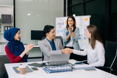 Genç iş adamları başarıyı kutluyor ve ofiste yaratıcı bir tasarım planlıyor.