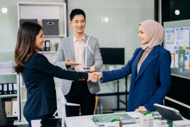 Çok ırklı iş adamlarından oluşan bir grup, konut projesinden yola çıkarak bina modeline bakıyor ve el sıkışıyor. Yeşil iş şirketi ve Güneş Enerjisi Çevre Kenti Kavramı.