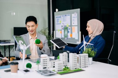 Çok ırklı iş adamlarından oluşan bir grup, konut projesinden bir yapı modeline bakıyor. Yeşil iş şirketi ve Güneş Enerjisi Çevre Kenti Kavramı.