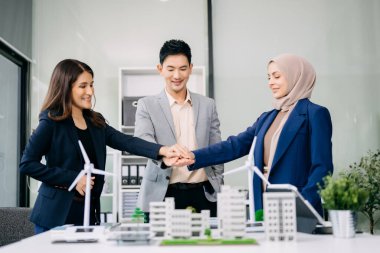 Çok ırklı iş adamlarından oluşan bir grup, konut projesinden yola çıkarak bina modeline bakıyor ve el sıkışıyor. Yeşil iş şirketi ve Güneş Enerjisi Çevre Kenti Kavramı.