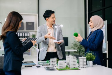 Çok ırklı iş adamlarından oluşan bir grup, konut projesinden bir yapı modeline bakıyor. Yeşil iş şirketi ve Güneş Enerjisi Çevre Kenti Kavramı.