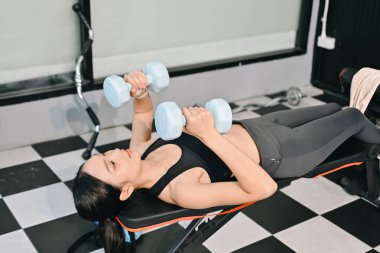 Spor salonunda kilo veren, halterlerle egzersiz yapan kararlı Asyalı kadın. Spor ve eğlence konsepti. Spor giyim sektöründe güzel bir kadın 