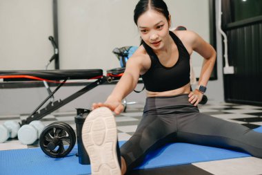 Azimli Asyalı kadın spor salonunda kilo veriyor ve un üzerinde egzersiz yapıyor. Spor ve eğlence konsepti. Spor giyim sektöründe güzel bir kadın 