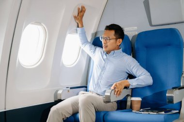 Uçakta oturmuş kendini tutmaya çalışan korkmuş bir adamın fotoğrafı.