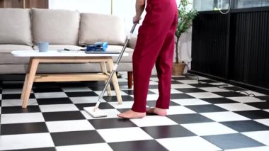 Genç Asyalı kadın evini paspasla temizliyor. Milenyum ev hanımı ev işlerini yapıyor, ev temizliği yapıyor.