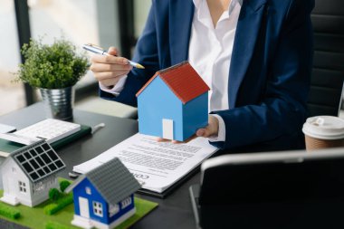 Emlak komisyoncusu ev modelini sunar. İş kadını, ofisteki ipotek kredisi teklifiyle ilgili müşteriye danışıyor 