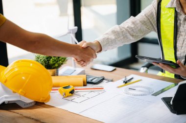 İki mimarın orta bölümü, ofiste yeni bir projeye başlamak için el sıkışıyor. 