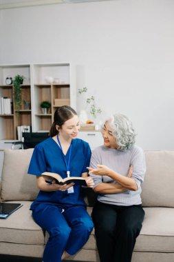 Evde kanepede oturan yaşlı hastayla ilgilenen genç bayan doktor. 