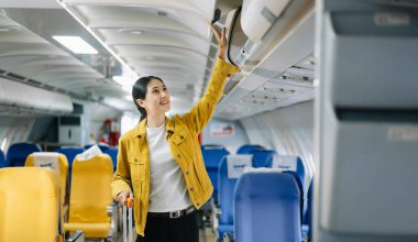 Çekici Asyalı bayan yolcu bavuluyla uçağa bindi.