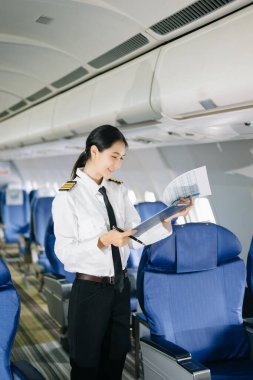 Asyalı, kendine güvenen, üniformalı kadın pilot, uçağın içinde poz veriyor.