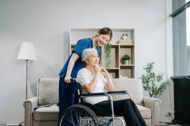 Evde elmalı hemşire ve kıdemli hasta. Tekerlekli sandalyede oturan yaşlı kadınla ilgilenen terapist. Tıbbi servis kavramı  