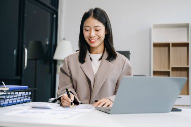 Genç ve güzel bir kadın çalıştığı yerde dizüstü bilgisayar kullanıyor. İşine odaklan..