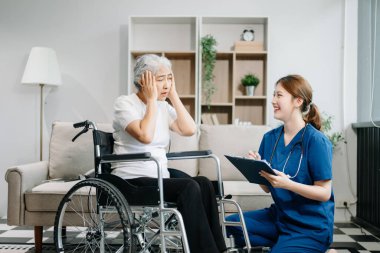Doktor evdeki yaşlı hastayı muayene ediyor. Kadın terapist elinde pano tutuyor ve tekerlekli sandalyede oturan yaşlı bir kadınla ilgileniyor. Tıbbi servis kavramı