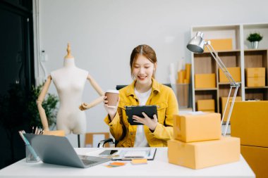 Moda tasarımcısı kadın stüdyoda dizüstü bilgisayar ve tablet kullanıyor. 