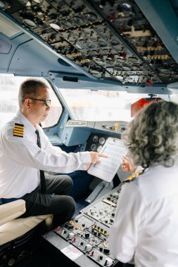 Olgun ticari erkek ve dişi pilotlar uçuş başlamadan önce hazırlanıyorlar.