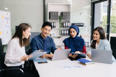 Çok ırklı genç yaratıcı insanlardan oluşan bir grup iş görüşmelerini tartışıyor fikir üreten tasarım projelerini ofisinde tartışıyor.