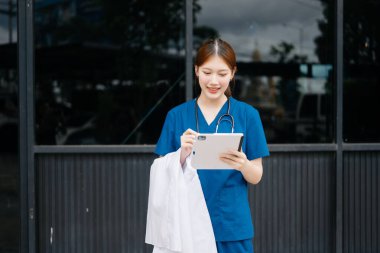 Hastanenin dışında dijital tablet kullanan genç Asyalı kadın doktor. 