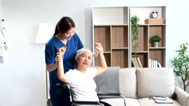 Fizyoterapist, hastane ofisinde egzersiz sırasında yaşlı bir kadının tekerlekli sandalyesini germesine yardım ediyor.