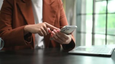 Ofiste akıllı telefon kullanan genç bir kadının orta bölümü..