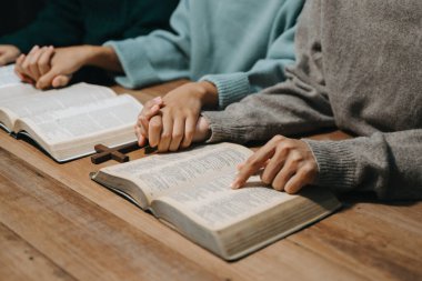 Bir grup Hıristiyan birlikte oturup ahşap bir masanın etrafında otururlar ve sınıfta bulanık incille dua ederler. Allah 'ın lütuf ve ihsanını dileyin..