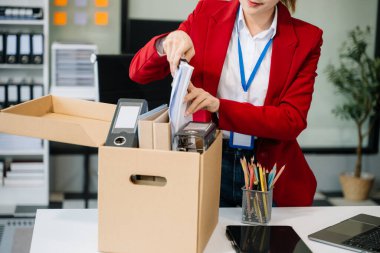 Mutlu ve heyecanlı genç Asyalı kadın ofis çalışanı istifasını kutluyor, kişisel eşyalarını taşıyor. Modern ofiste işi bırakmak, değiştirmek ya da şirket kurmak.
