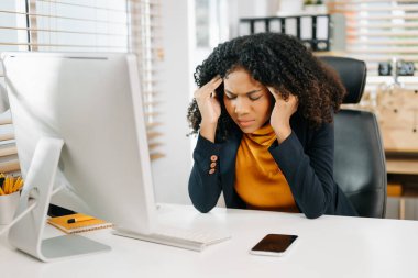 Çok çalışan Afrikalı Amerikalı iş kadını ofis çalışanı ofis masasında çalışırken yorgun hissediyor.