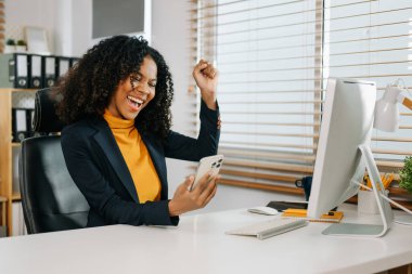 Ofiste çalışan Afrikalı Amerikalı genç bir kadın akıllı telefondan bir video görüşmesi yaptı.