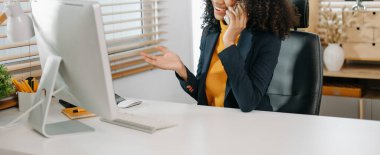 Modern ofiste çalışan Afro-Amerikan genç iş kadını akıllı telefon kullanıyor.