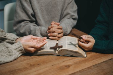 Hıristiyanlar, Allah 'ın lütfunu kazanmak için el ele tutuşurlar. Tahta masada.