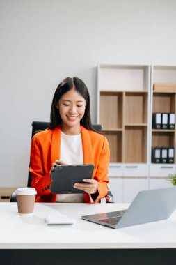 Modern ofiste ofis masasında tablet ve laptop kullanan bir iş kadını. 